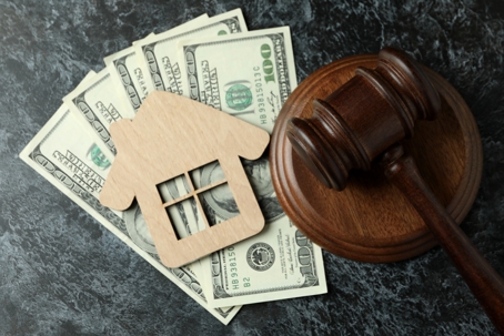 money, wooden house cutout, and a gavel